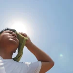 man wiping his forehead in the hot summer sun